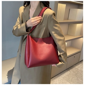 Détail d'un sac cabas vintage en similicuir bordeaux porté avec un trench kaki chic