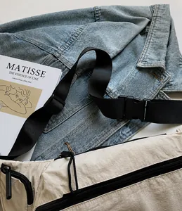 Détail de la bandoulière réglable en nylon noir et de la boucle sur le sac crème