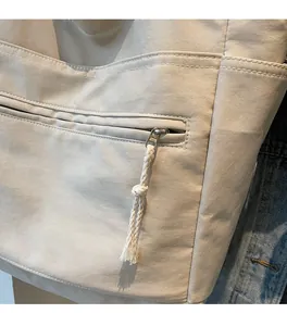 Détail d'un sac cabas en toile beige avec poche zippée avant et cordon tissé