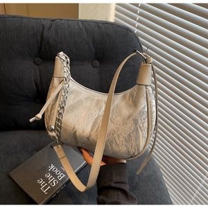 Close-up of silver wrinkled metallic hobo bag with thick chain and brand logo