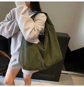 Lifestyle view of a large olive green nylon shoulder bag with a relaxed slouchy design