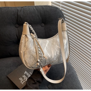 Detail of silver metallic dumpling bag with pleated texture and silver chain strap