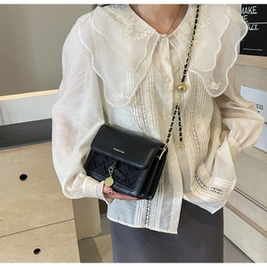 Détail du sac bandoulière matelassé noir avec chaîne dorée et boule de réglage en métal