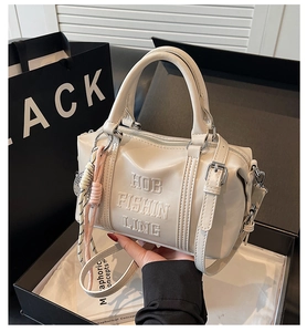 Detailed close-up of a cream Boston handbag with embossed text inside a gift box