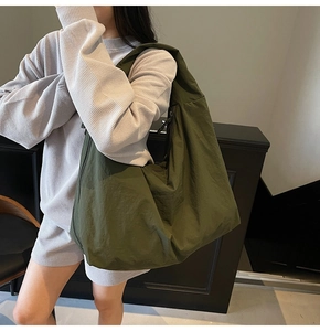 Detalle del bolso tote de nailon verde militar con correa ancha para el hombro en modelo