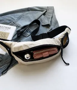 Détail de l'intérieur d'un sac bandoulière en nylon beige montrant un grand rangement