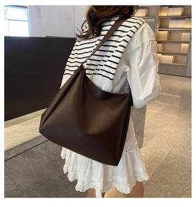 Vue détaillée d'un grand sac cabas vintage en similicuir marron porté par un mannequin