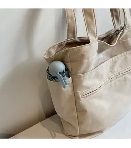 Détail de la poche latérale d'un sac cabas en toile beige avec un parapluie plié