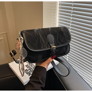 Detail of black pleated crossbody bag featuring a silver tennis racket charm and strap