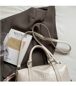 Detail of cream Boston bag with HOB embossing and adjustable smooth long strap