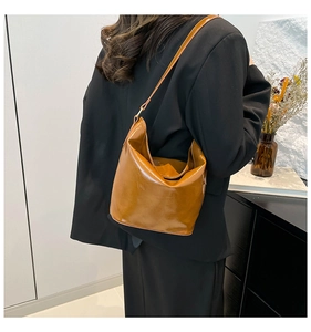 Close-up of caramel leather tote bag with curved design and slim shoulder strap
