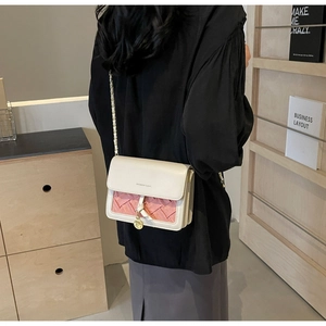 Détail du sac à chaîne beige et rose avec texture tressée porté par un mannequin
