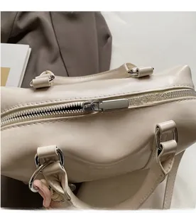 Close-up of smooth silver metal zipper and fine stitching on beige leather handbag
