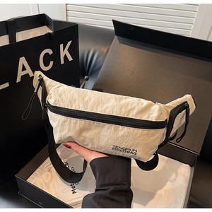 Détail du sac bandoulière en nylon blanc cassé avec fermeture éclair noire et logo