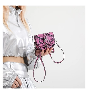 Detailed view of pink snake print mini saddle bag with silver metal ring buckle on model