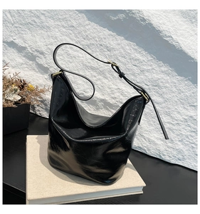 Detail of black glossy cracked leather hobo bag with adjustable strap and gold hardware