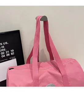 Details der rosa Reisetasche mit stabilen Webgriffen und silberner Smiley-Stickerei am Beutel