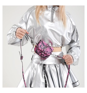 Detail of vibrant pink snakeskin saddle bag with silver buckle worn by a model
