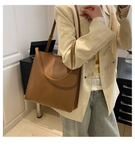 Brown faux leather tote bag worn by a model in a professional office setting