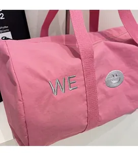 Nahaufnahme der rosa Reisetasche mit WE-Stickerei und glattem schwarzem Reißverschluss