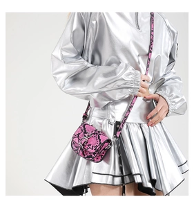 Close-up of pink snakeskin mini saddle bag with silver buckle on a stylish model