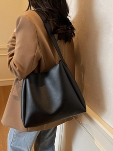 Grand sac cabas minimaliste en cuir PU noir porté par un mannequin dans un bureau chic