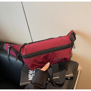 Détail du sac bandoulière bordeaux en nylon avec tissu texturé et fermetures éclair