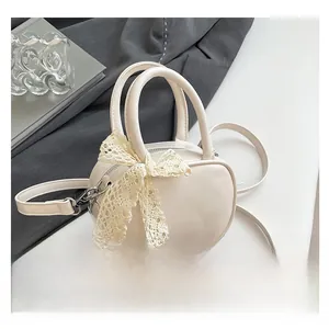 Detail of a creamy white mini handbag featuring a lace bow and smooth leather texture