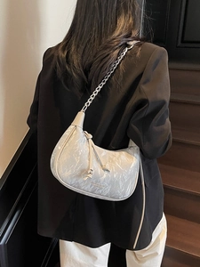 Chic pleated pearl white crescent bag with metal chain strap shown on model shoulder
