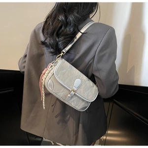 Silver grey pleated shoulder bag with a woven charm shown on a charcoal blazer