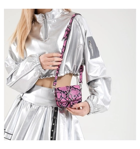 Close-up of fuchsia snakeskin print mini saddle bag with silver buckle worn by model