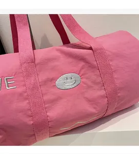 Detail der rosa Segeltuch-Reisetasche mit gesticktem Smiley und verstärkten Griffen