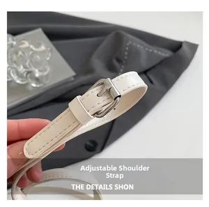 Macro view of adjustable cream leather shoulder strap with silver buckle and neat stitching