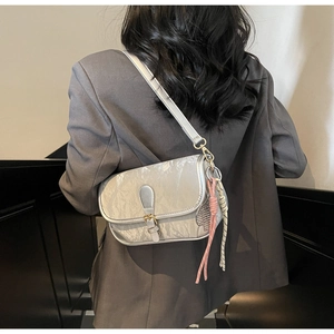 Detail of silver textured crossbody bag featuring metallic buckle and braided cords