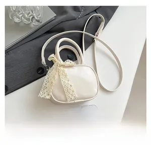 Detail of cream mini crossbody bag with lace bow and smartphone for size reference