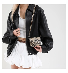 Detailed view of a mini snakeskin saddle bag paired with a black faux leather jacket