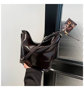 Close-up of glossy chocolate brown patent leather tote with adjustable shoulder strap