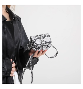 Mini crossbody saddle bag featuring black and white snakeskin pattern worn by a model