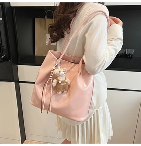 Detail of pink faux leather tote bag featuring a cute teddy bear charm on shoulder strap