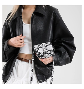 Detail of a chic black faux leather jacket paired with a snakeskin print crossbody bag