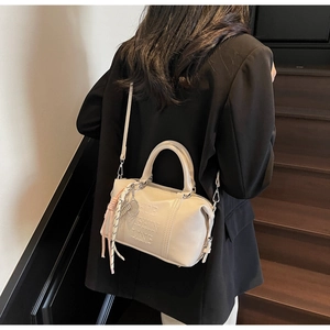 Detalle del bolso bowling de cuero crema con relieve HOB FASHION LINE y borla tejida