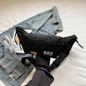 Détail de la texture en nylon noir et du lettrage blanc sur le sac à bandoulière épuré
