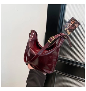 Detail of dark red glossy hobo bag with adjustable strap and golden metallic buckle