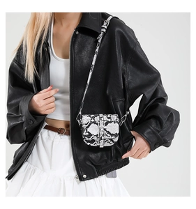 Close-up of black-white snakeskin pattern mini saddle bag with metal hardware on model