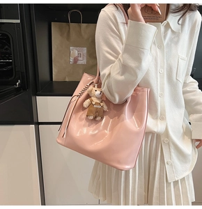 Detailed shot of pink glossy tote bag featuring a cute teddy bear charm and sleek finish