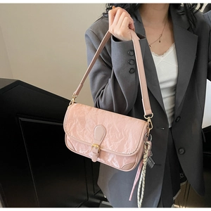 Close-up of pink wrinkled texture shoulder bag with metallic buckle and woven charm