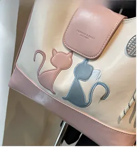 Close-up of dual-tone tote bag featuring cat embroidery and metallic mesh detail