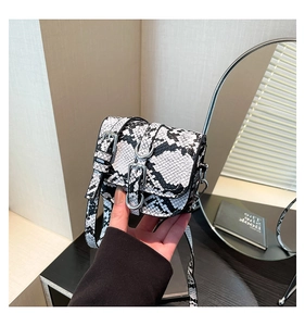 Close-up of black and white snakeskin pattern mini saddle bag with silver buckle