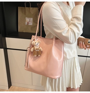 Pink PU leather tote bag with a brown bear pendant shown on model in a modern interior