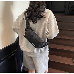 Sac de poitrine urbain noir en nylon avec logo blanc porté par un mannequin chic